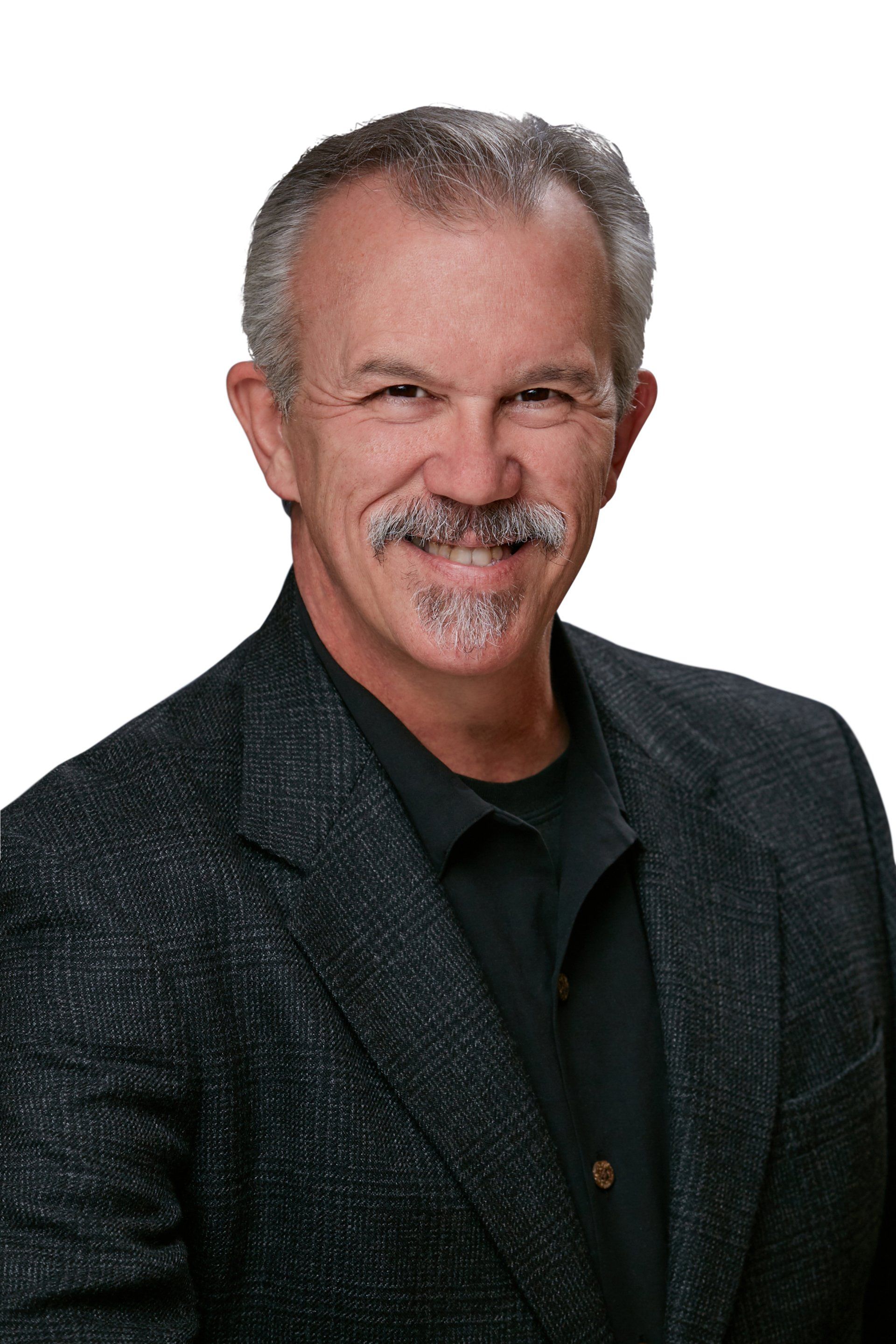 Portrait of a smiling man in a dark blazer and black shirt against a white background