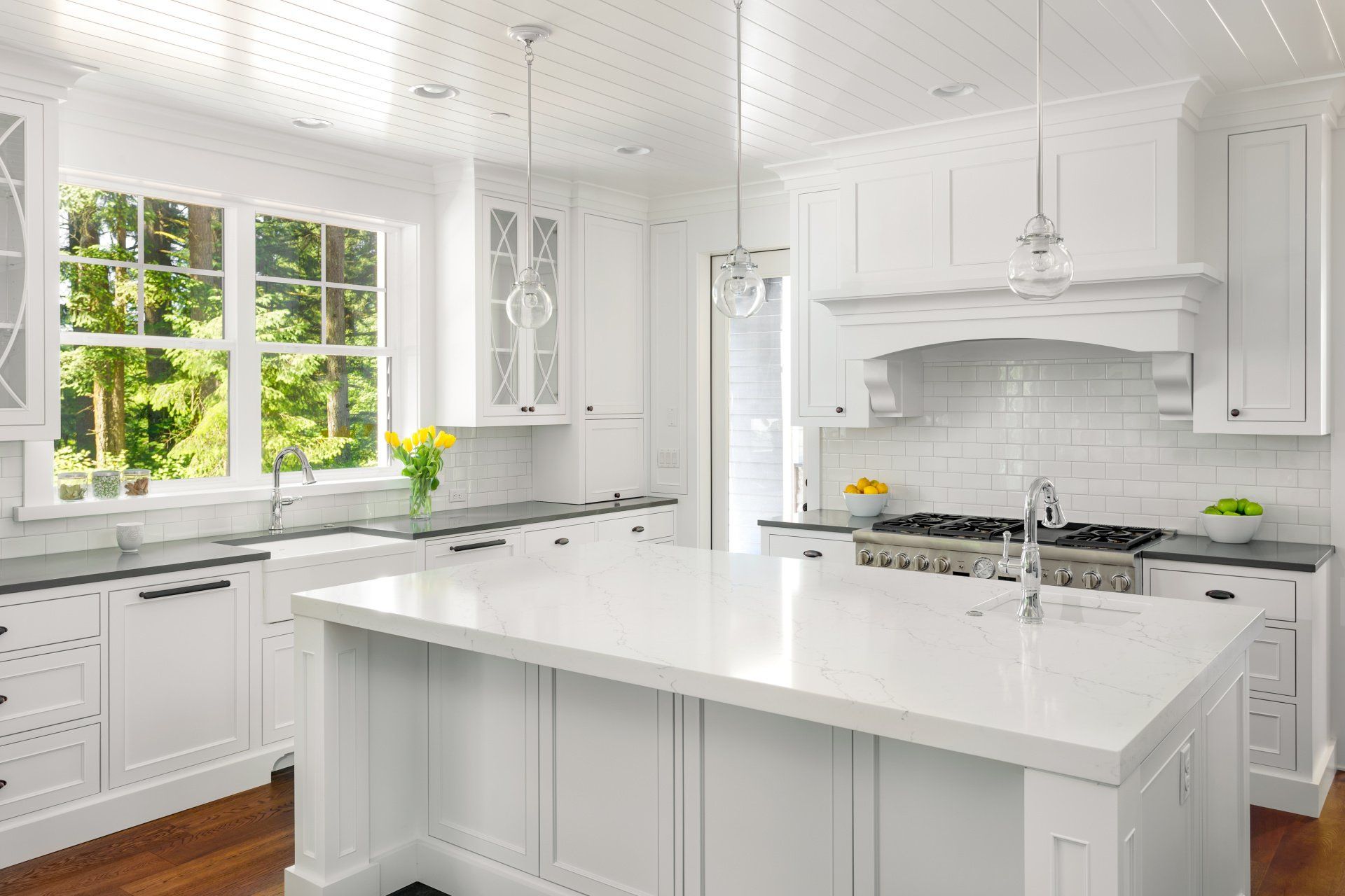 A kitchen with white cabinets and a large island in the middle.