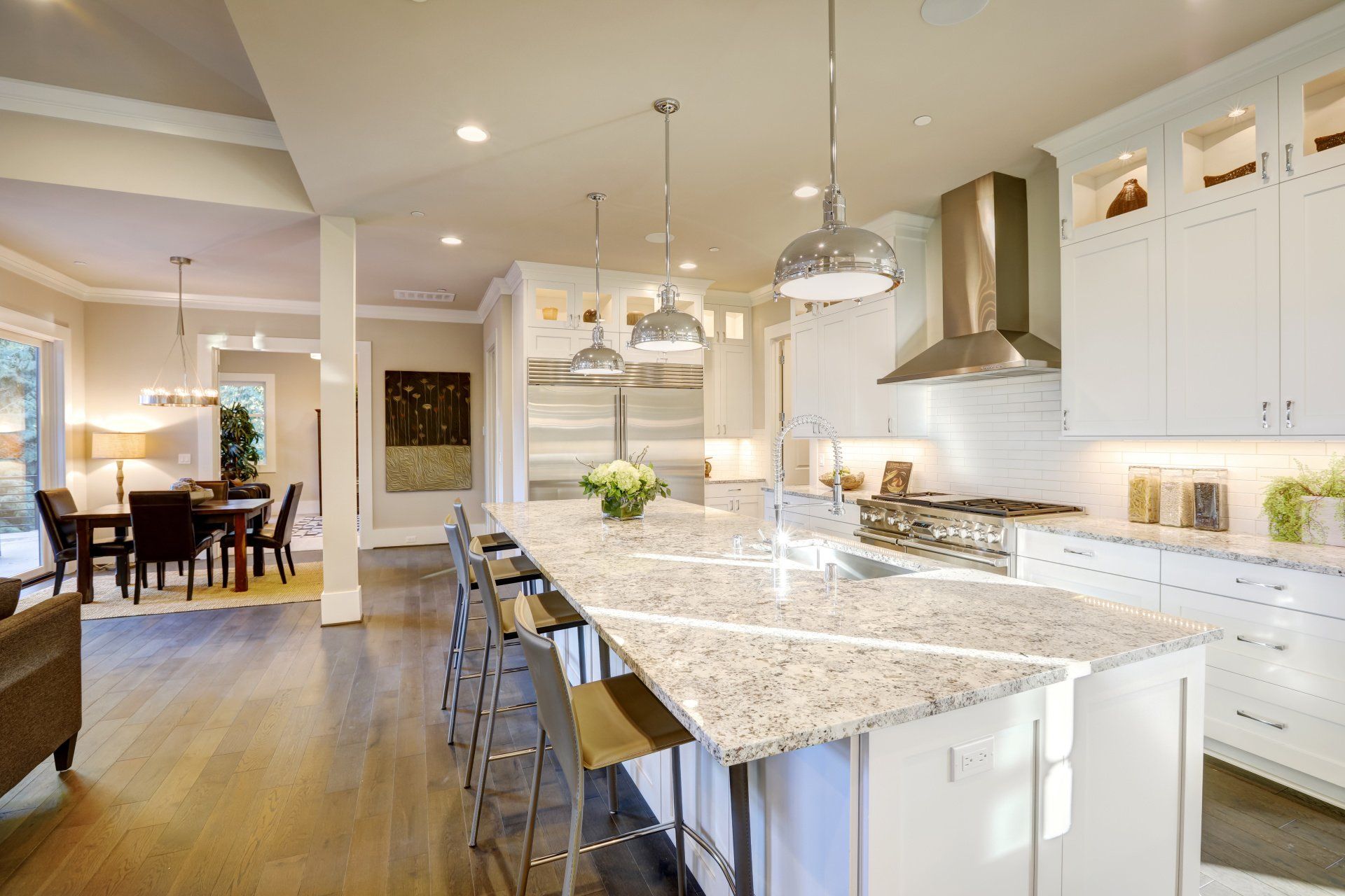 A kitchen with granite counter tops , white cabinets and stainless steel appliances.