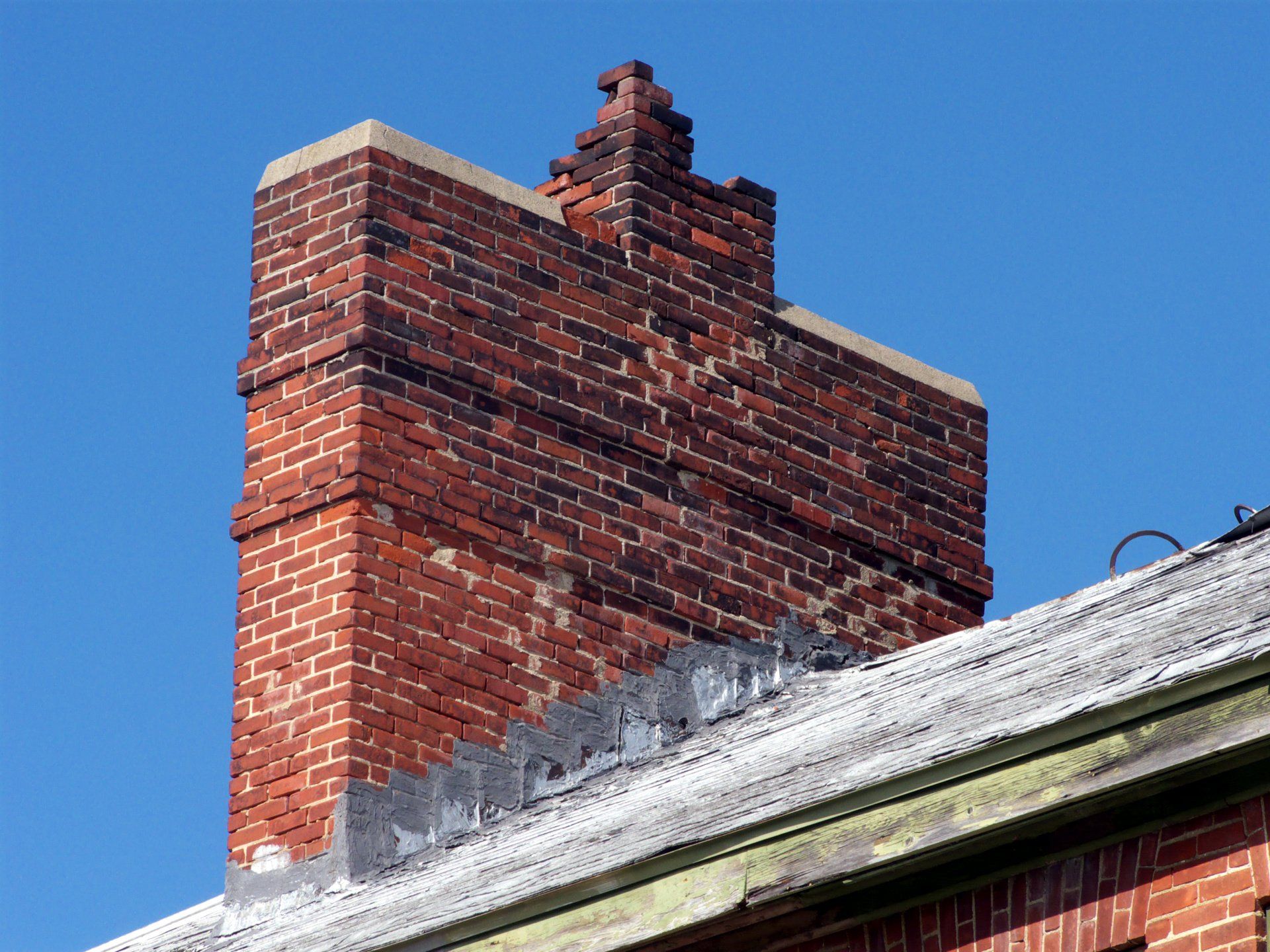 A brick chimney is sitting on top of a brick building.