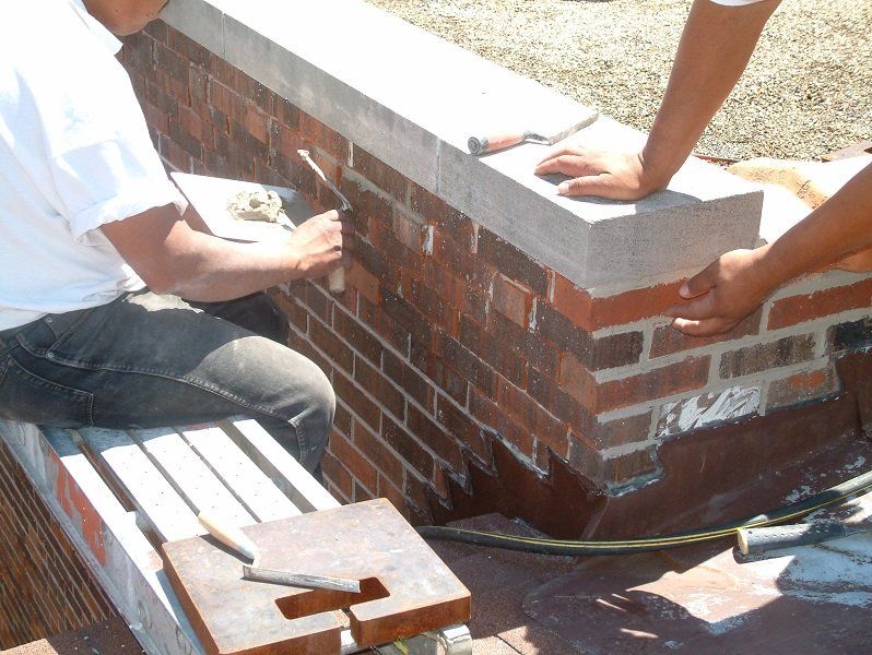 Two men are working on a brick wall with tools