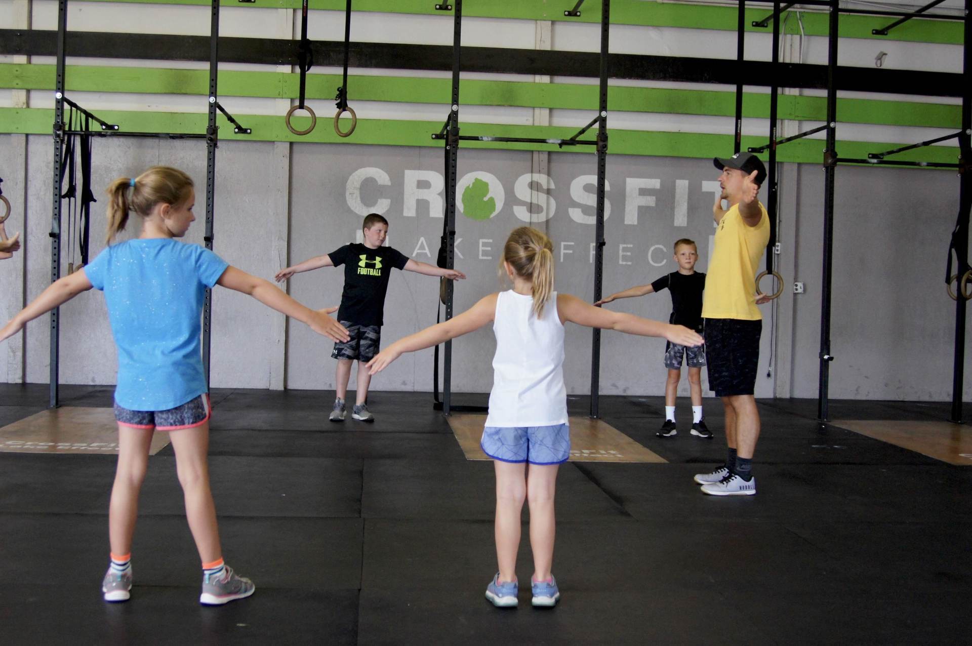 A group of children are doing stretching exercises in a gym.