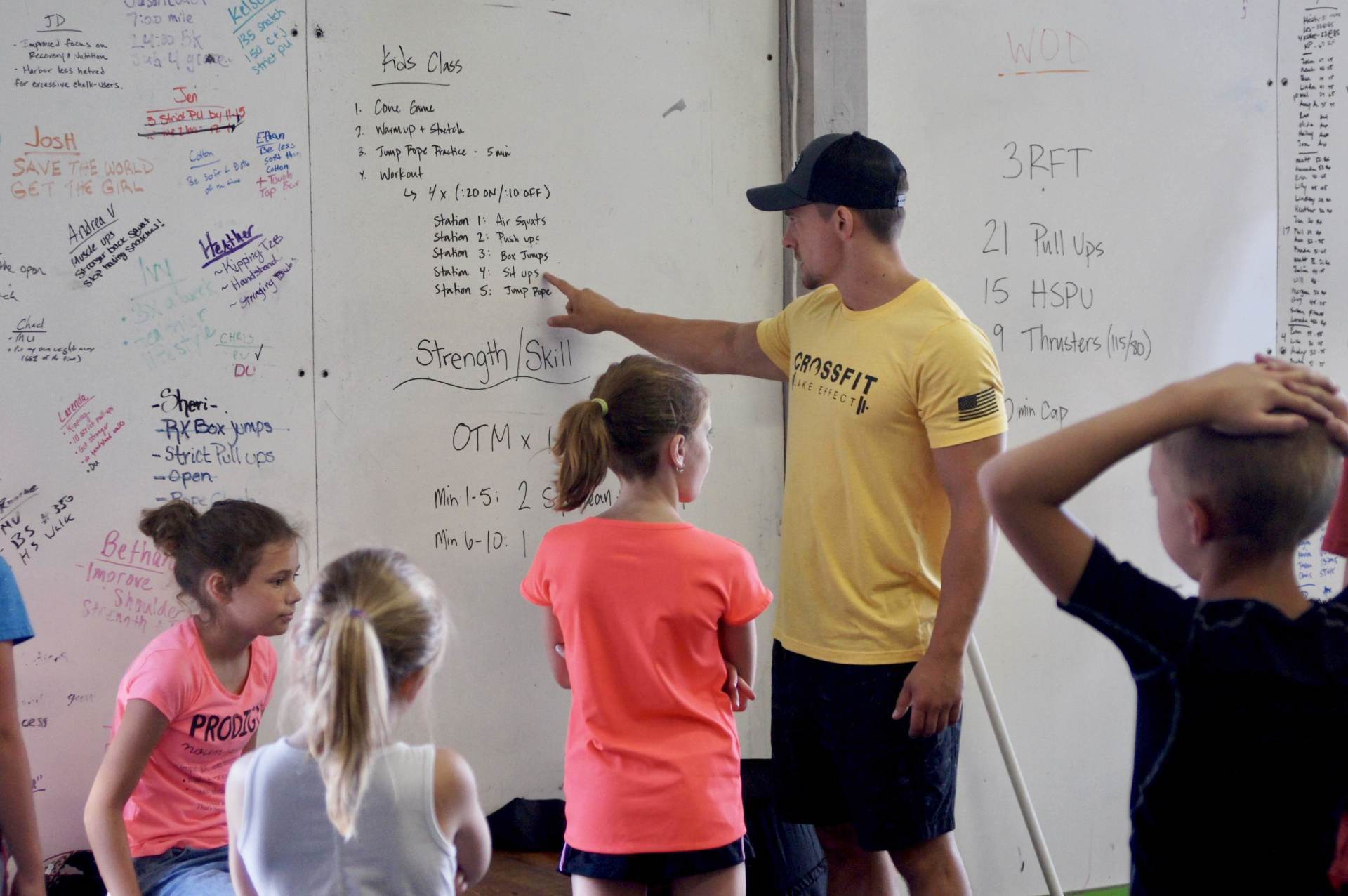 A man in a yellow shirt is pointing at something on a white board