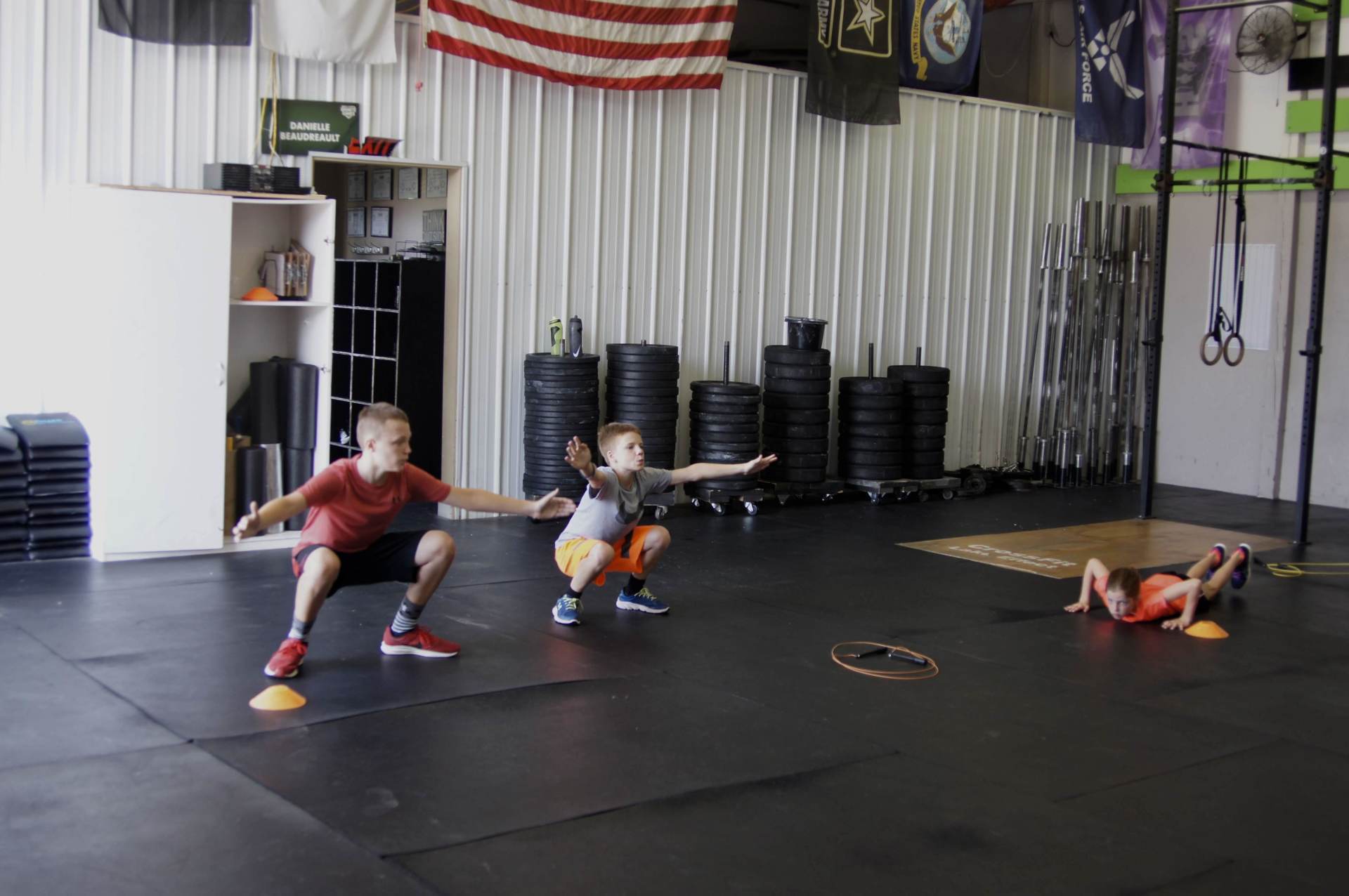 A group of young children are doing squats in a gym.