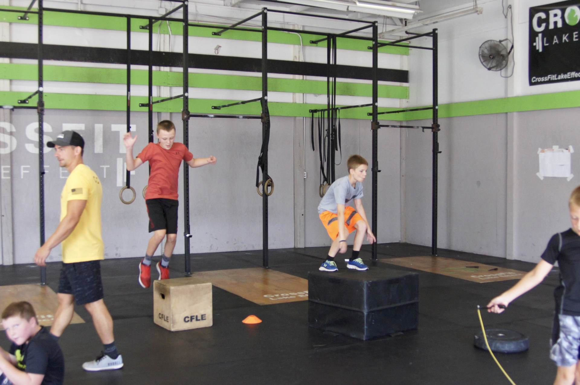 A group of young boys are jumping over boxes in a gym.