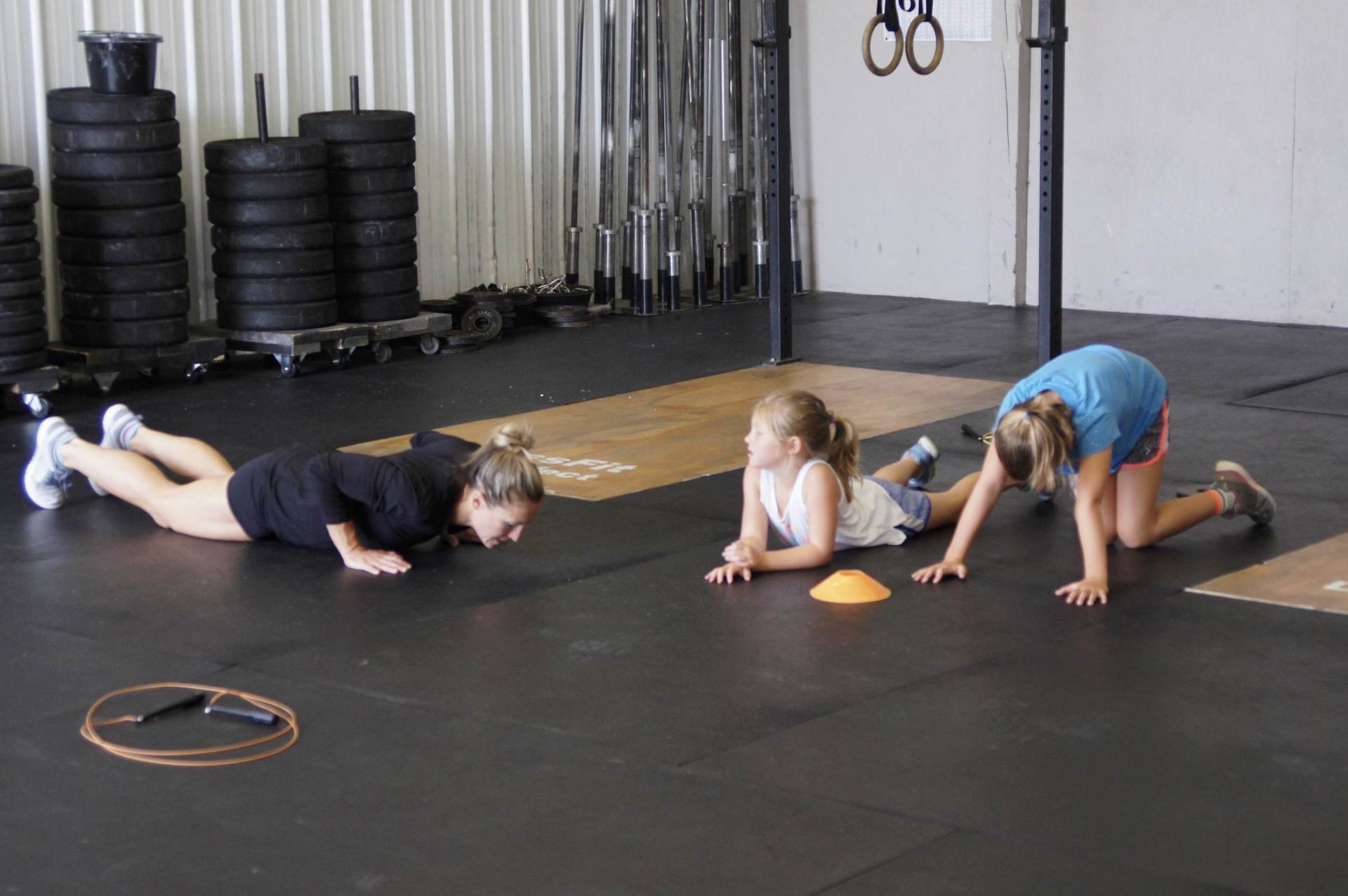 Two girls are doing push ups on the floor in a gym.