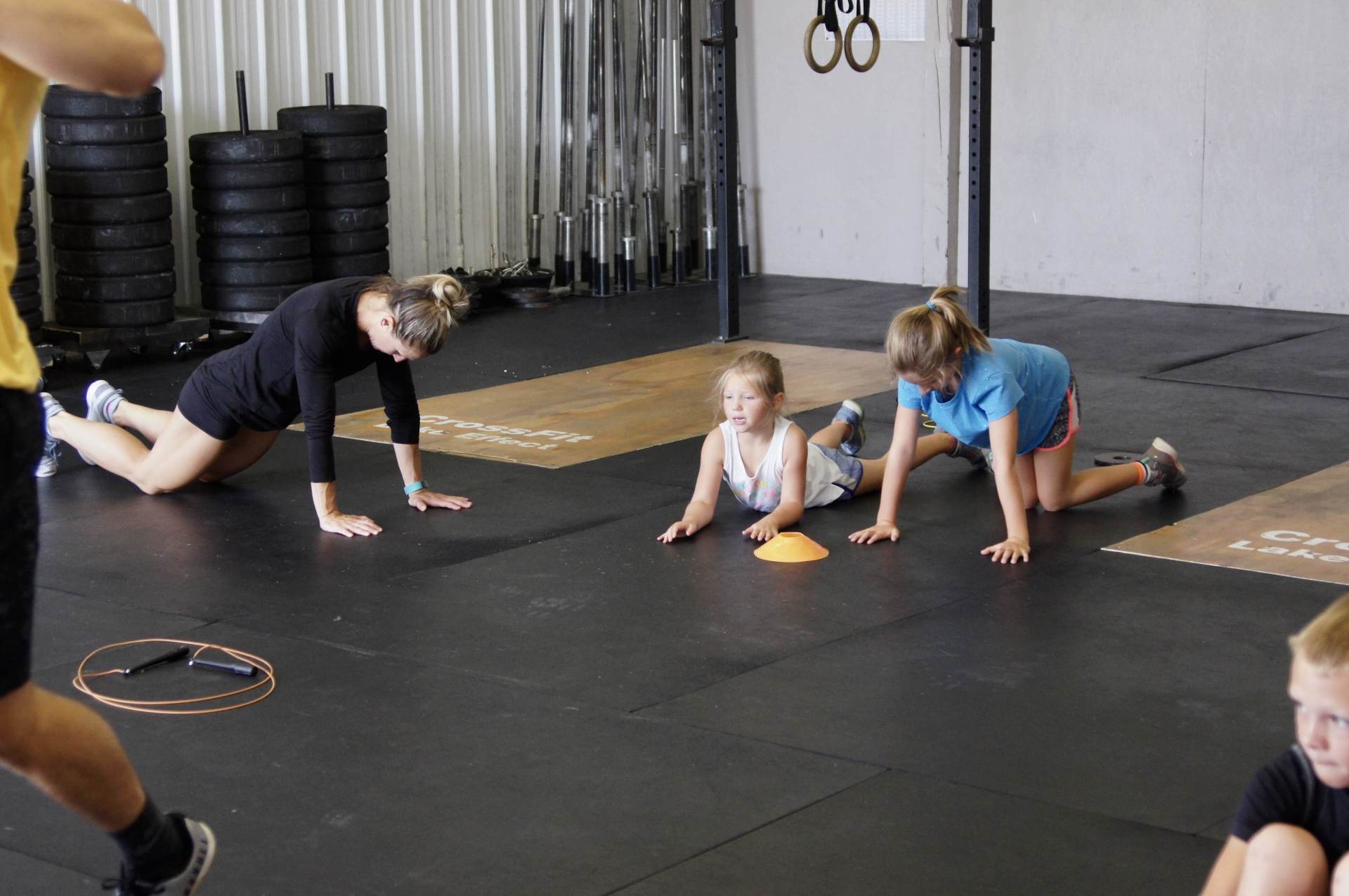 A group of people are doing push ups on the floor in a gym.