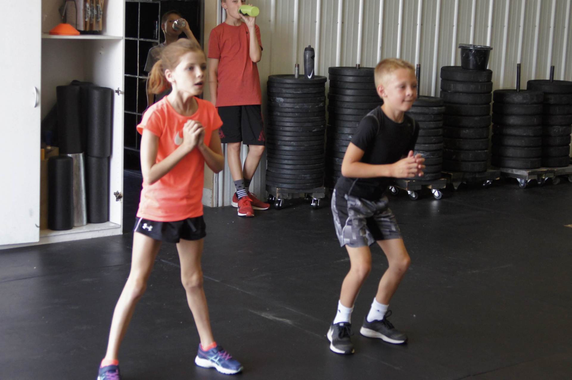 A boy and a girl are doing exercises in a gym.