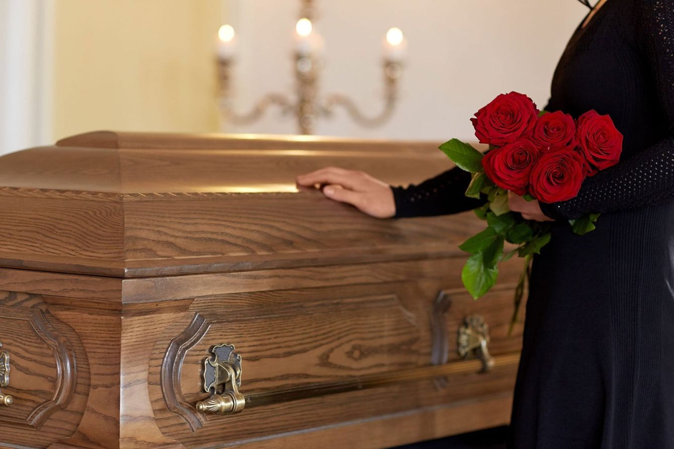 Donna che porta un mazzo di fiori in omaggio alla bara di un defunto