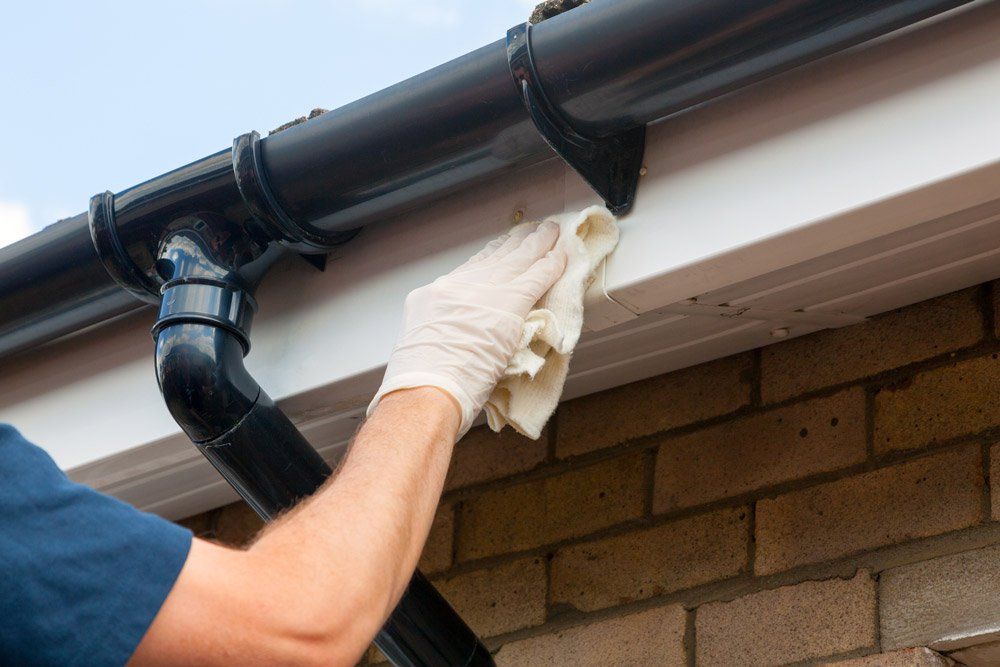 Roofing Northboro — Person Cleaning Plastic Guttering in West Boylston, MA