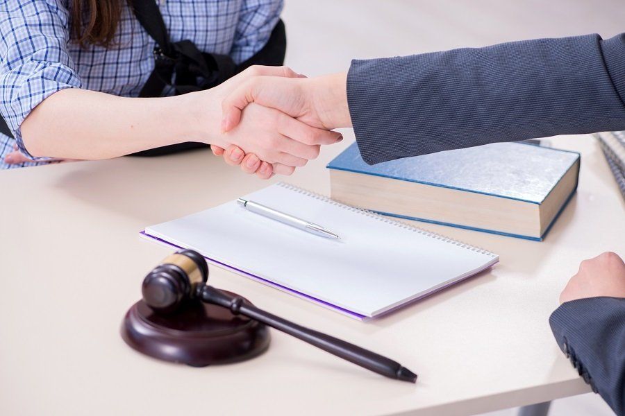 a injured woman wearing an arm sling shaking hands with an attorney