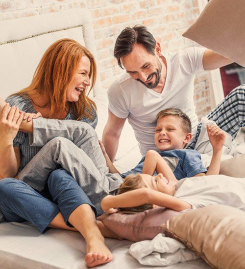 Term and Permanent Insurance — Happy Family Playing in Bed in Stevens Point,WI Term and Permanent Insurance — Happy Family Playing in Bed in Stevens Point,WI