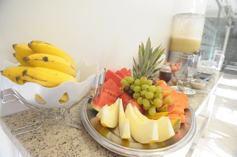 Um prato de frutas está sobre um balcão ao lado de uma tigela de bananas.