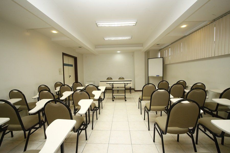 Uma sala de aula com mesas e cadeiras e um quadro branco