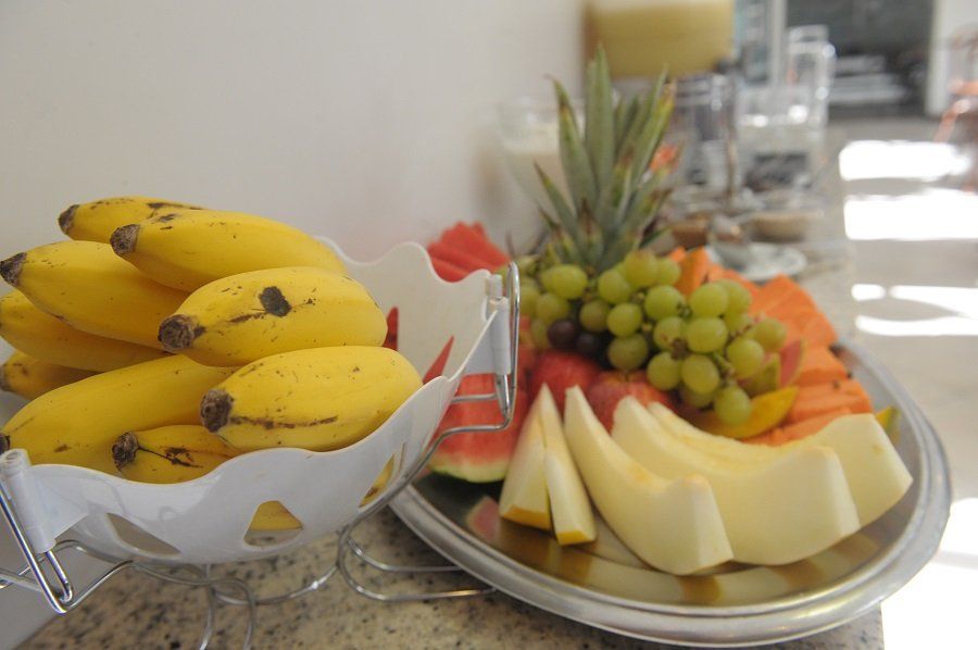 Uma tigela de bananas e um prato de frutas sobre uma mesa.