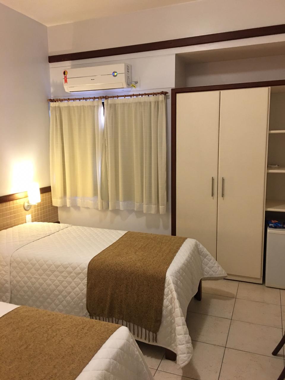 Um quarto de hotel com duas camas e uma geladeira