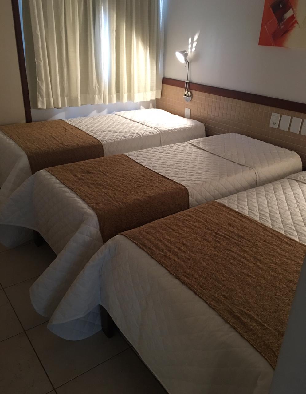 Um quarto de hotel com três camas e uma janela