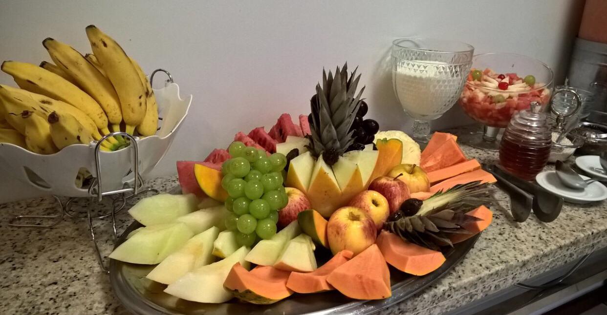 Uma bandeja de frutas está sobre um balcão ao lado de uma tigela de bananas.