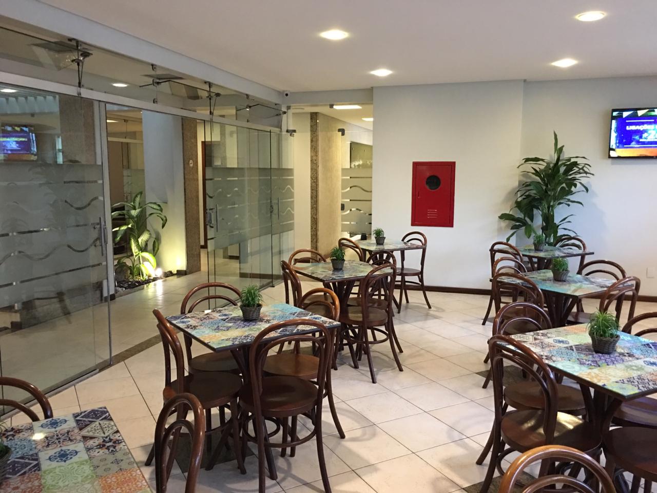 Um restaurante com mesas e cadeiras e uma televisão na parede.