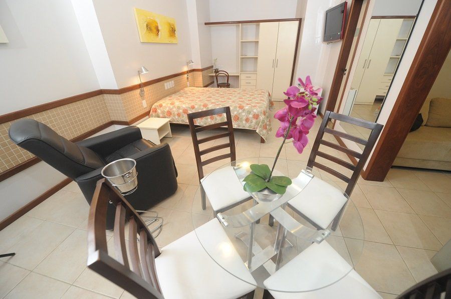 Um quarto de hotel com mesa e cadeiras de vidro - Portal da Princesa