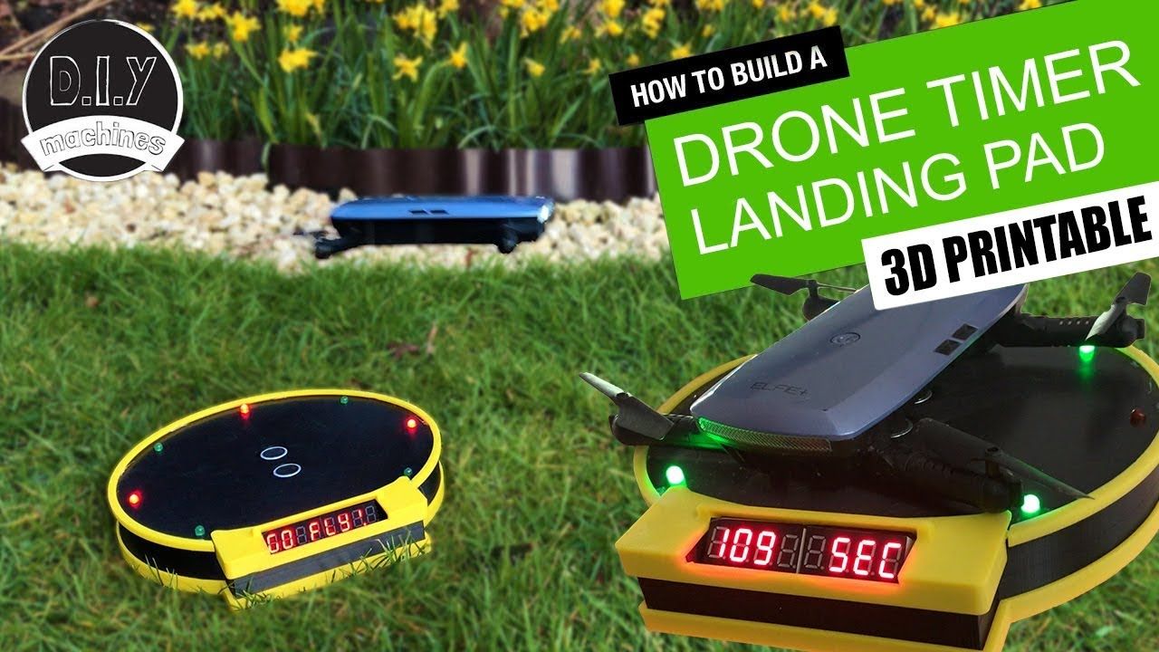 Two 3D-printed yellow and black drone landing pads with built-in digital timers sit on a grassy lawn.