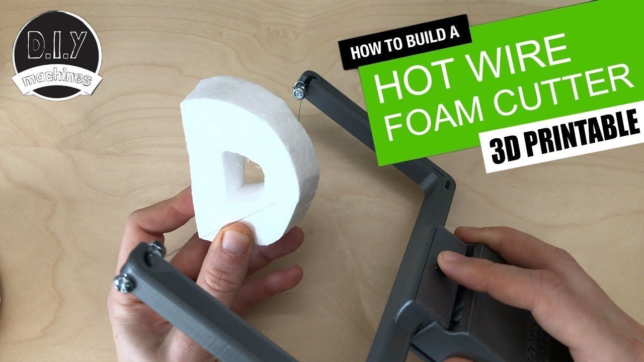 Hands holding a 3D printed hot wire foam cutter and a piece of foam shaped like the letter D on a wooden background.