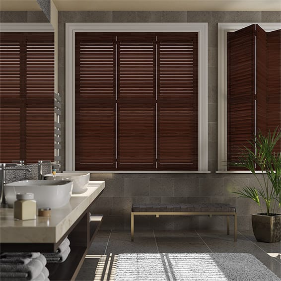 Bathroom with brown shutters, sink, bench, potted plant, and tiled walls and floor.
