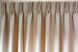 Beige pleated drapery hanging from a rod.