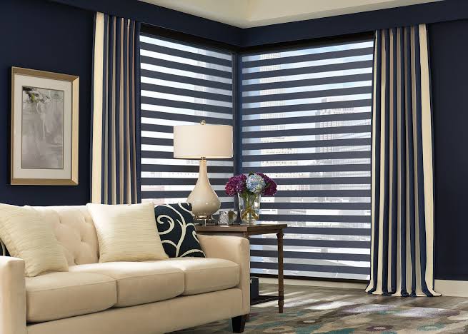 Living room with blue walls, beige sofa, striped curtains, and layered blinds.