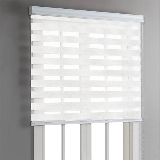 White and cream striped zebra blinds on a window against a gray wall.