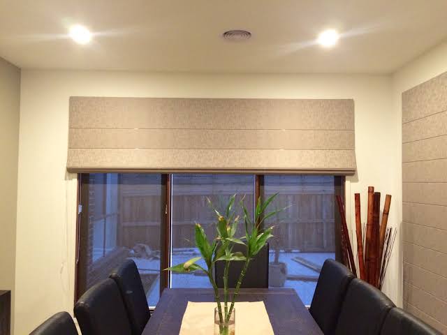 Dining room with a long table set for guests, closed Roman shade on window.
