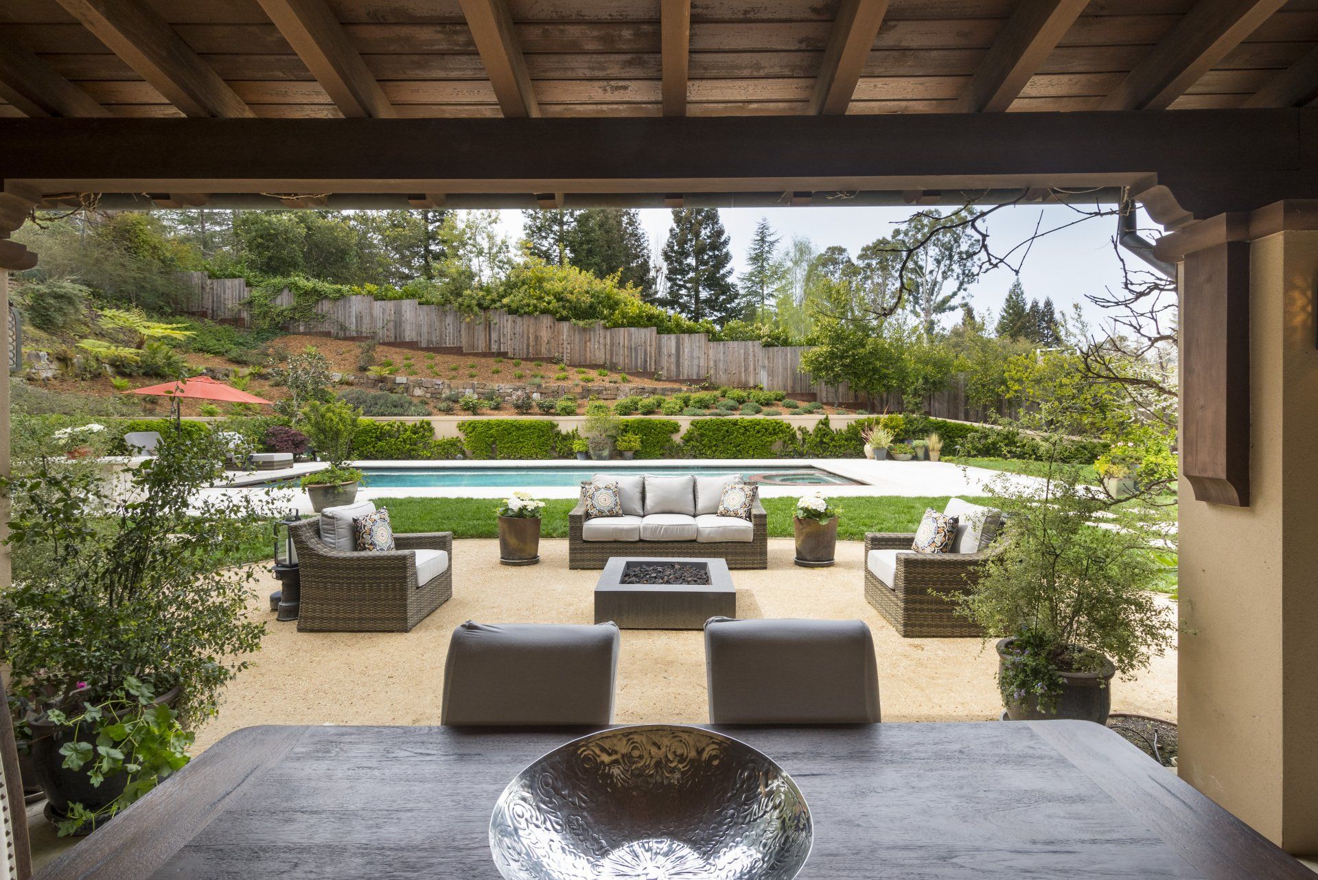 Patio with outdoor furniture overlooking a pool and landscaped yard.
