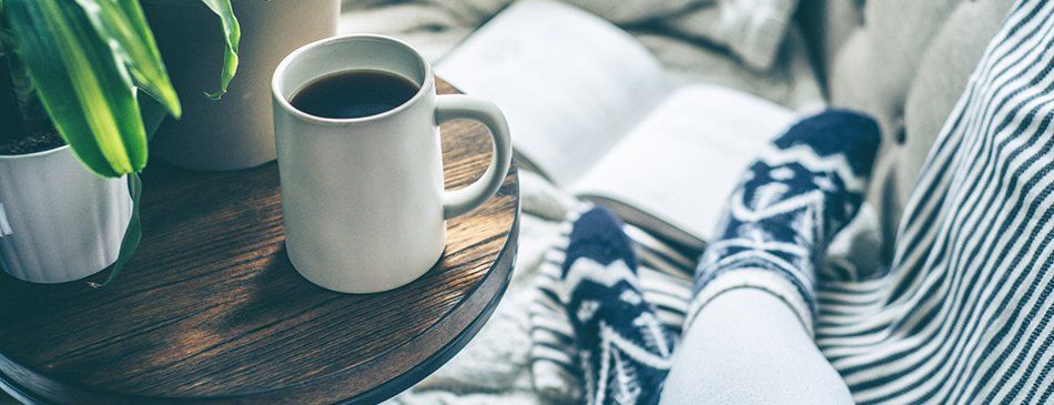 Drinking Coffee and reading a book on the couch | Sirott Properties