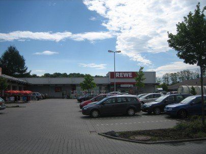 晴れた日に車が駐車されている REWE スーパーマーケット。