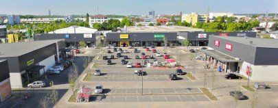Eine Luftaufnahme eines Einkaufszentrums mit Parkplatz und mehreren Geschäften.