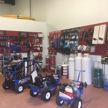 Hardware store interior with pressure washers, tanks, and tools on display.