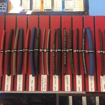 Hoses displayed on a red board with labels, secured by metal clamps. Various colors and thicknesses.