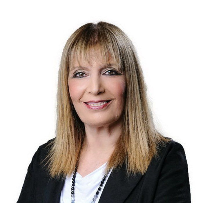 אישה לובשת ז'קט שחור וחולצה לבנה מחייכת למצלמה