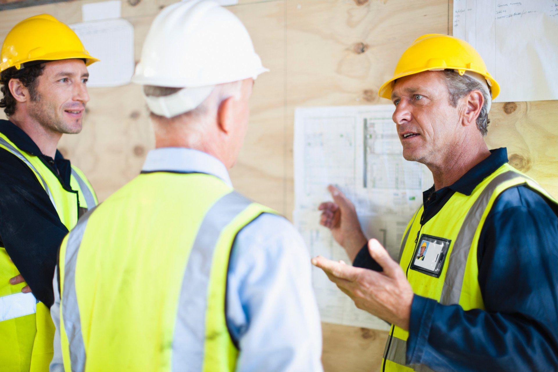 A group of construction workers are standing around talking to each other.