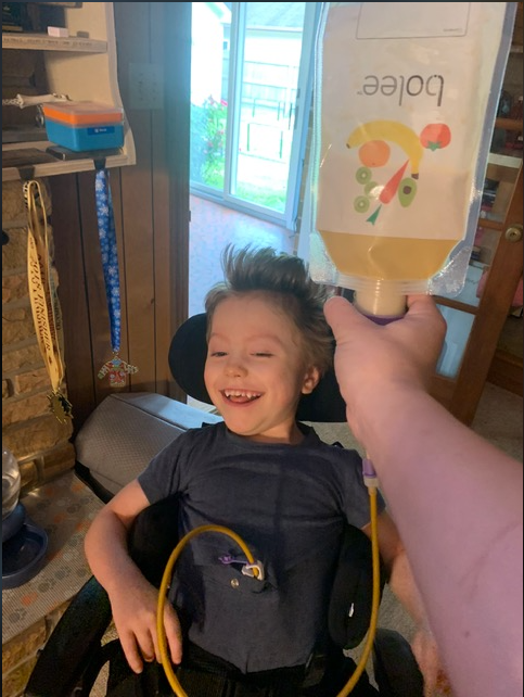 Young person with a parent holding the Bolee Bag while tube feeding