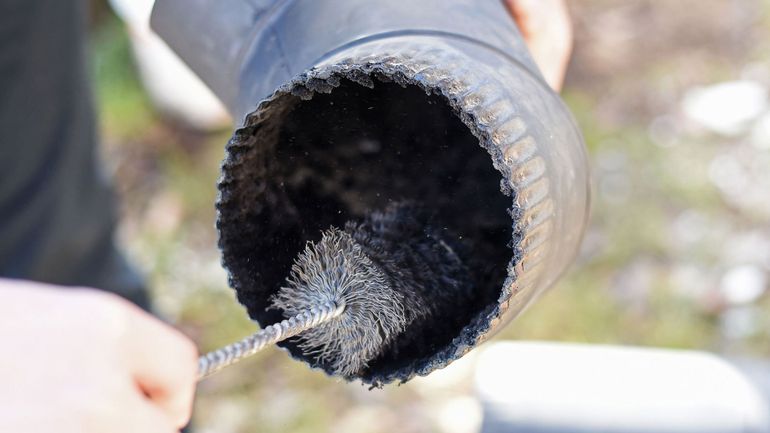 Cleaning a black pipe interior with a brush.