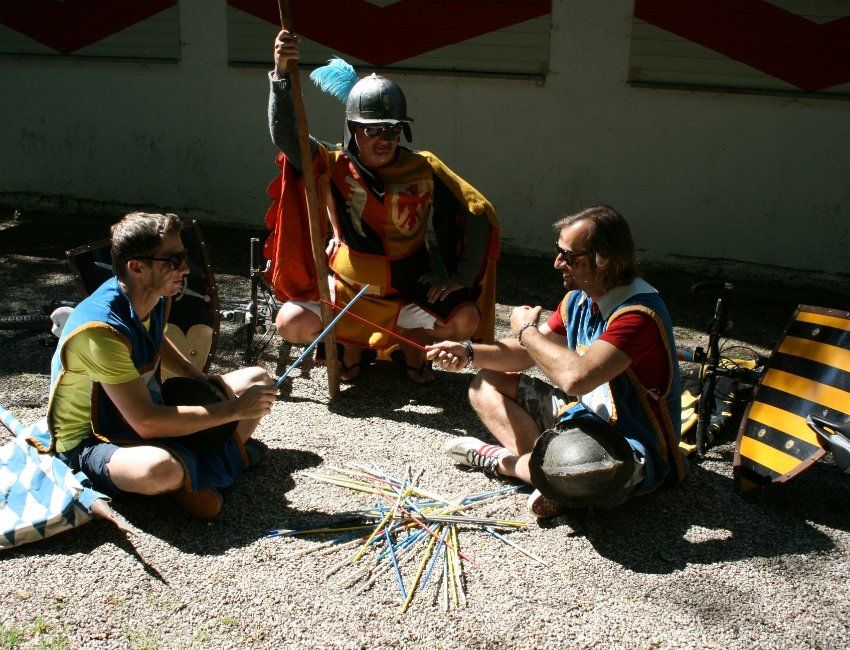 Drei Männer sitzen auf dem Boden und spielen Mikado