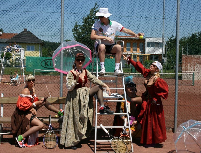 Eine Gruppe von Menschen in Kostümen auf einem Tennisplatz