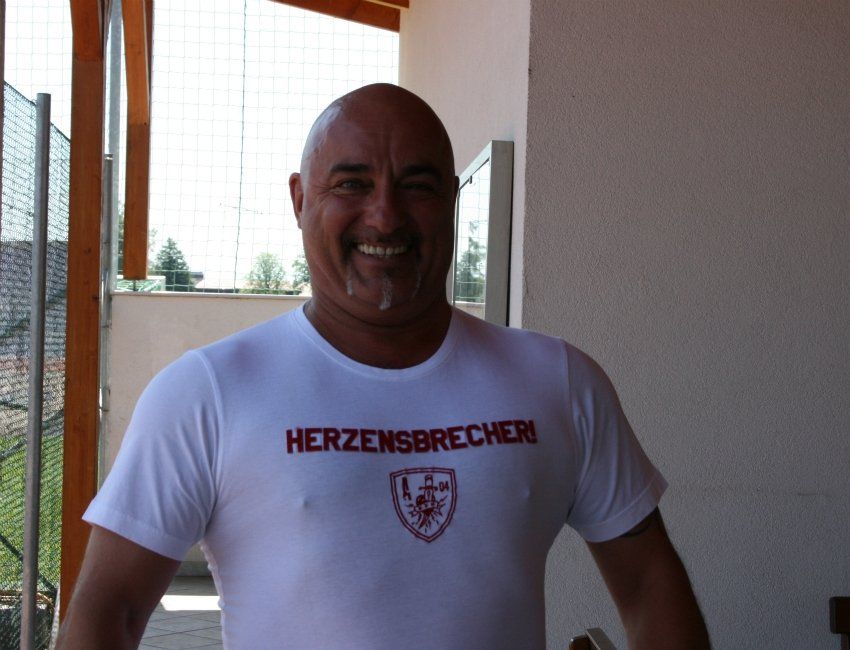 Ein Mann, der ein weißes Hemd mit der Aufschrift „Herzensbrecher“ trägt