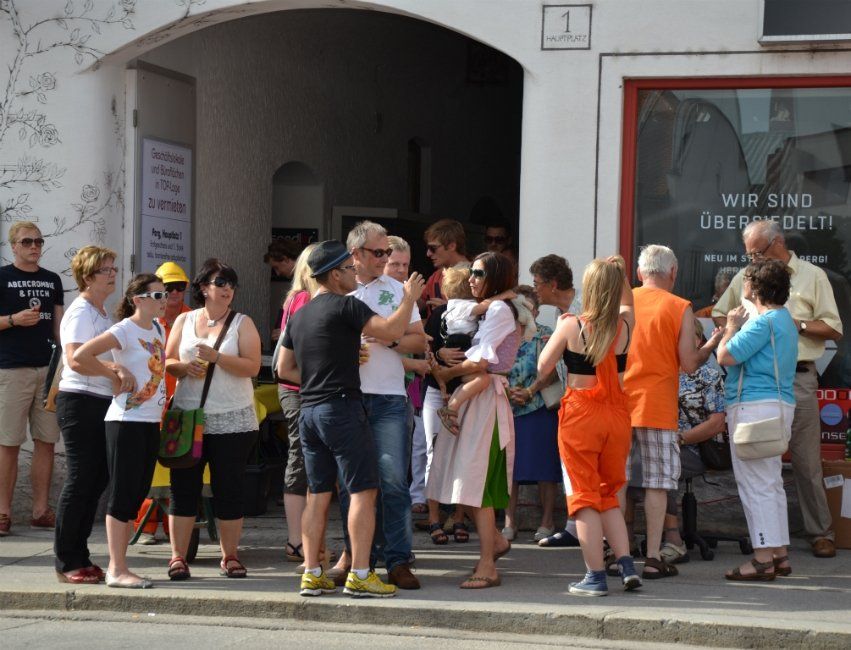 Eine Gruppe von Menschen steht auf dem Bürgersteig vor einem Gebäude.