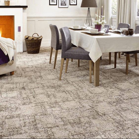 Dining room with a white tablecloth, gray chairs, and a light patterned carpet near a fireplace.