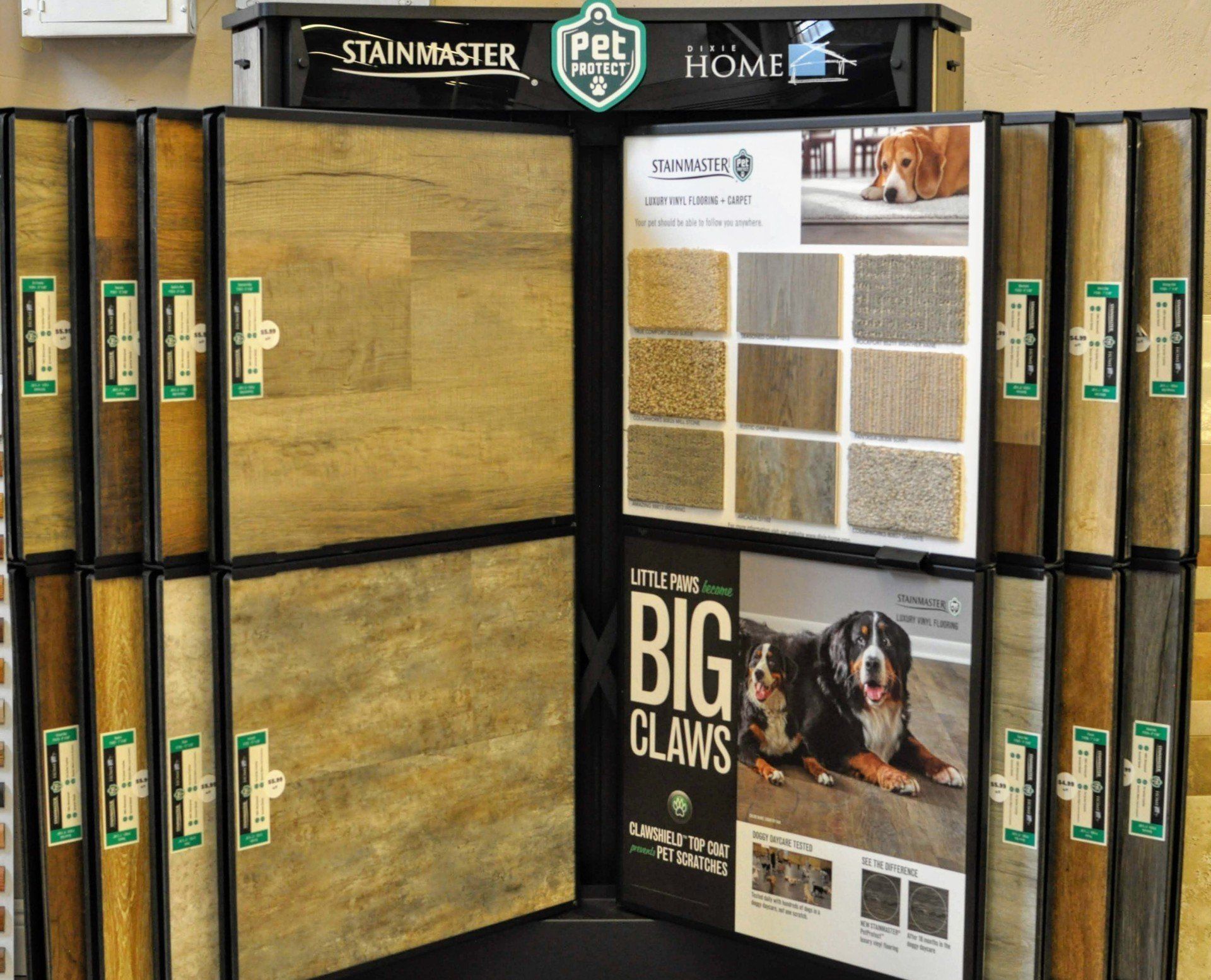 Carpet sample display with tan, brown, and black tiles in a flooring store, featuring a dog-themed ad.