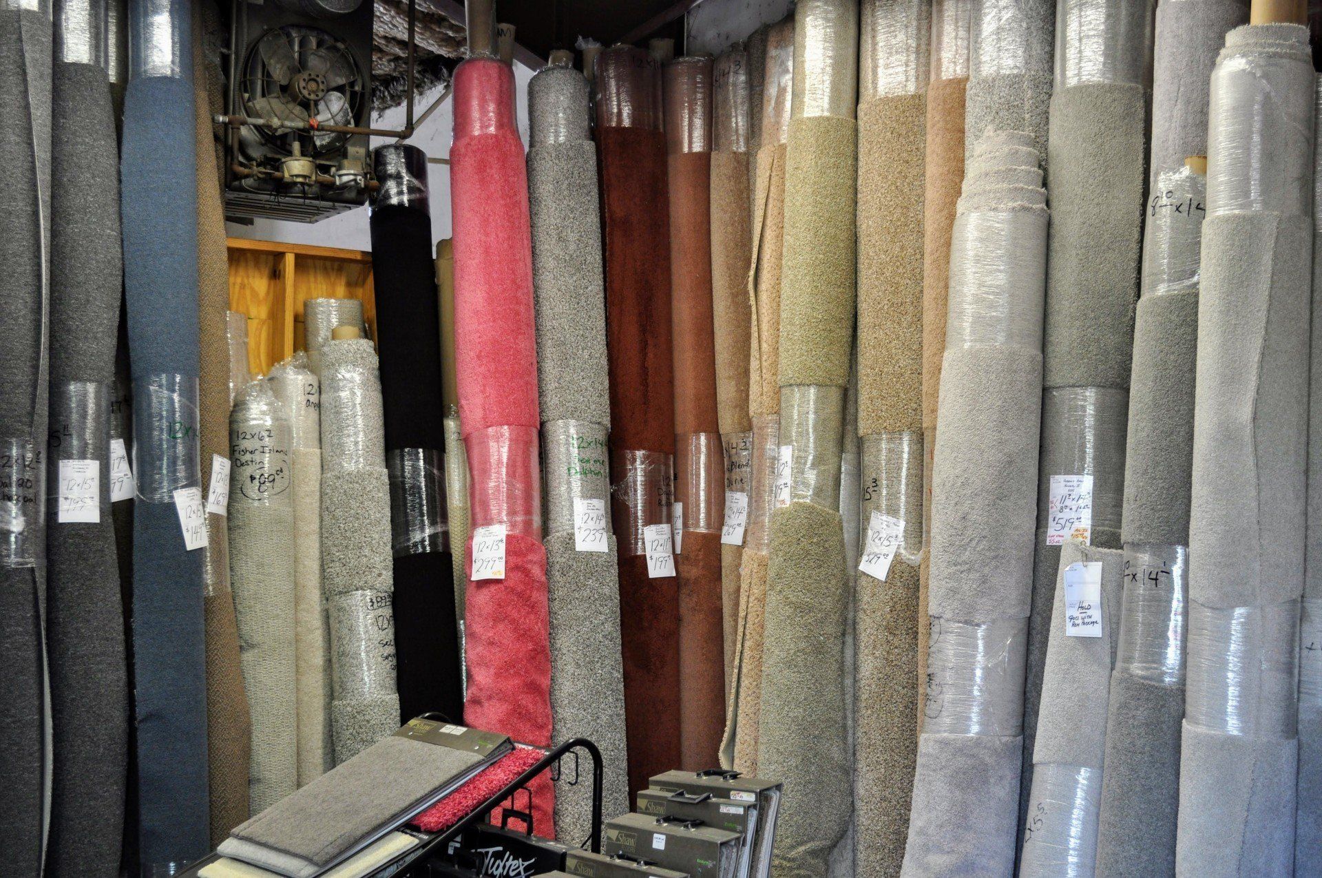 Rugs and carpet rolls displayed upright in a shop, in various colors and patterns