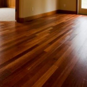 Polished wooden floor in an empty room with tan walls and bright light from the right
