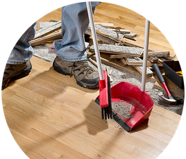 a person is cleaning a wooden floor with a broom and shovel .